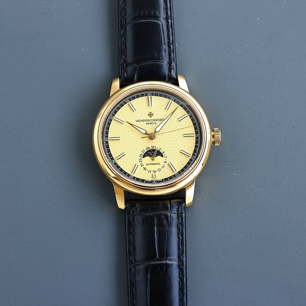 Vacheron Constantin watch with gold case, black leather strap, yellow dial and baton markers.