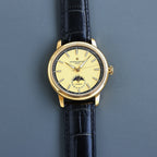 Vacheron Constantin watch with gold case, black leather strap, yellow dial and baton markers.