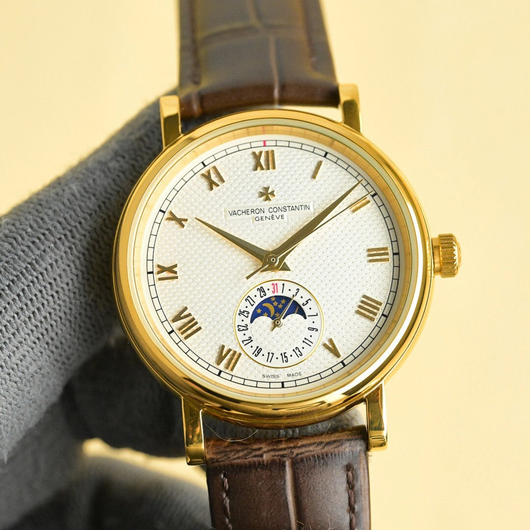 Vacheron Constantin watch with gold case, white dial, brown leather strap, Roman numerals.