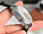 Stainless steel watch with black leather strap, angled side view of case and crystal.