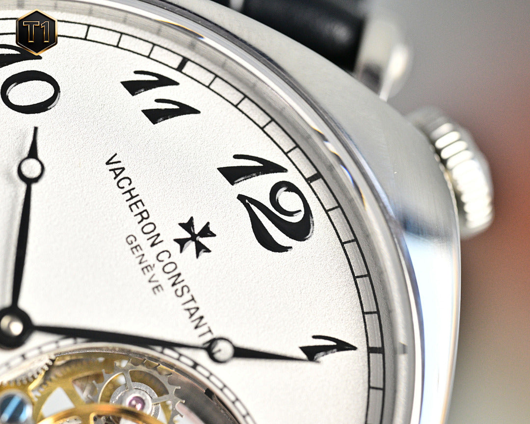 White dial watch with decorative numerals and skeleton opening, close-up.