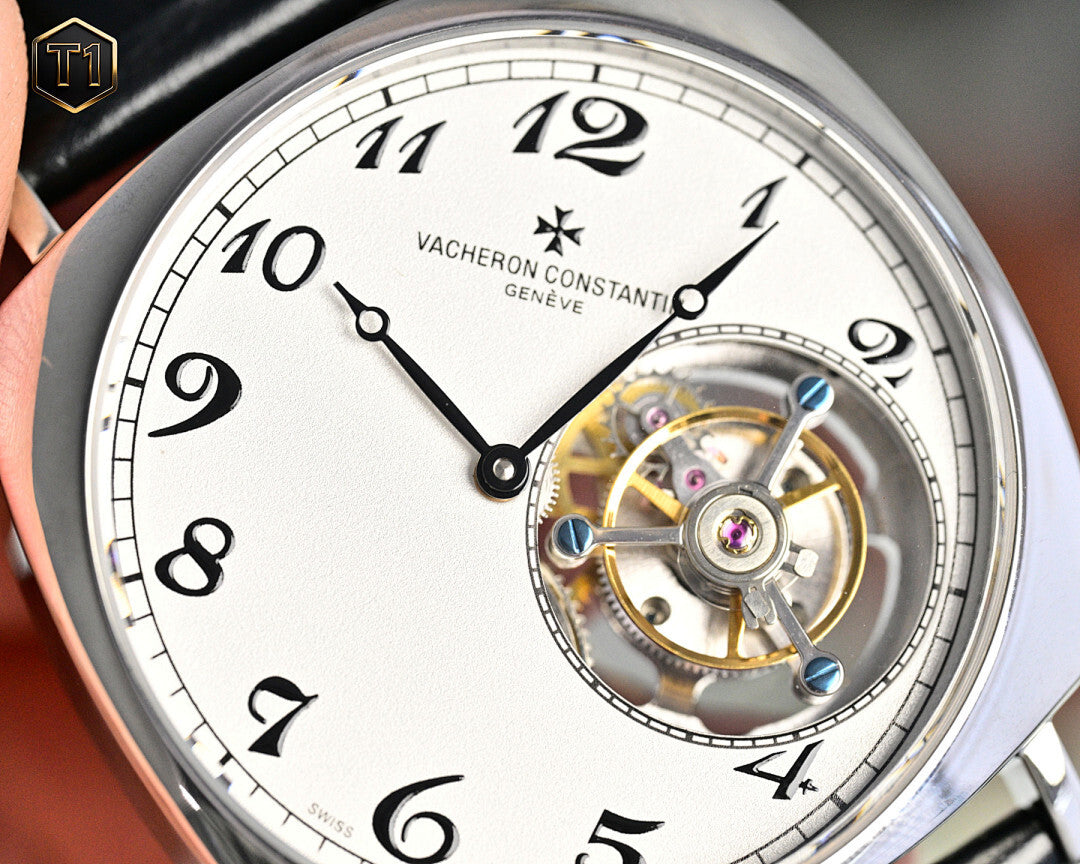 Stainless steel watch face with white dial, roman numerals, and exposed balance wheel.