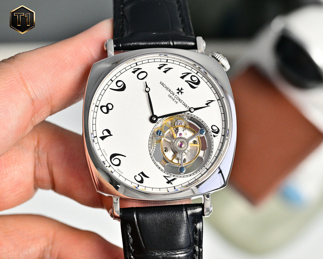 Stainless steel skeleton watch with black leather strap and white dial, front view in hand.