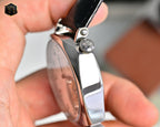 Stainless steel watch case with crown and black leather strap, side profile detail.