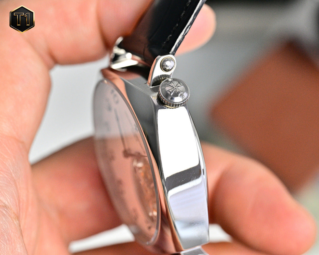 Stainless steel watch case with crown and black leather strap, side profile detail.