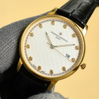 Gold Vacheron Constantin watch with white dial, diamond markers, black leather strap