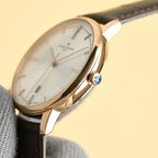 Vacheron Constantin watch with white dial, gold-tone case, and black leather strap