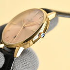 Luxury wristwatch with pale pink dial, gold bezel, visible crown and black leather strap