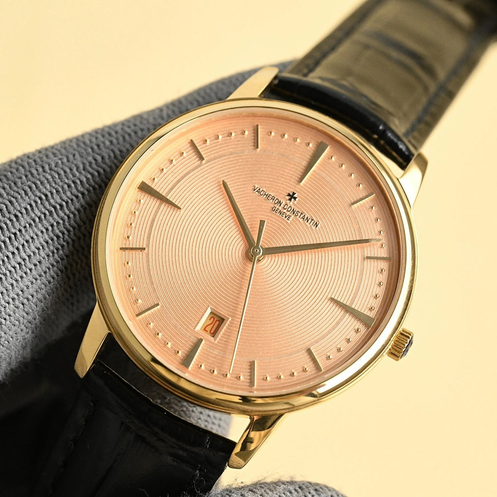 Luxury wristwatch with pink dial, gold case, black leather strap and date window
