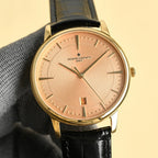 Luxury wristwatch with champagne dial, gold case, black leather strap and analog hands