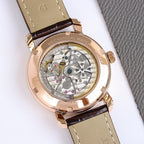 Mechanical watch caseback with visible gears, rose-gold tone, brown leather strap.