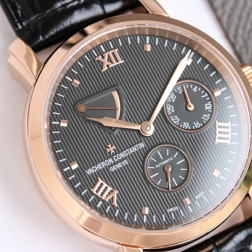 Gold-tone wristwatch with dark textured dial, Roman numerals, black leather strap.