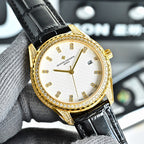 Gold-tone watch with white dial, black leather strap, jeweled bezel, date window