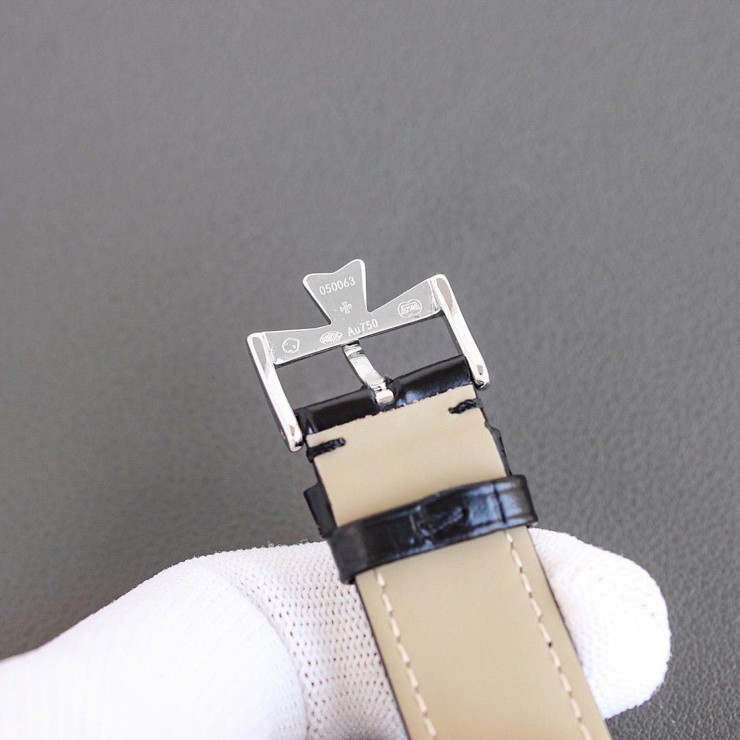 Black leather watch strap with silver buckle and clasp hardware on beige leather backing