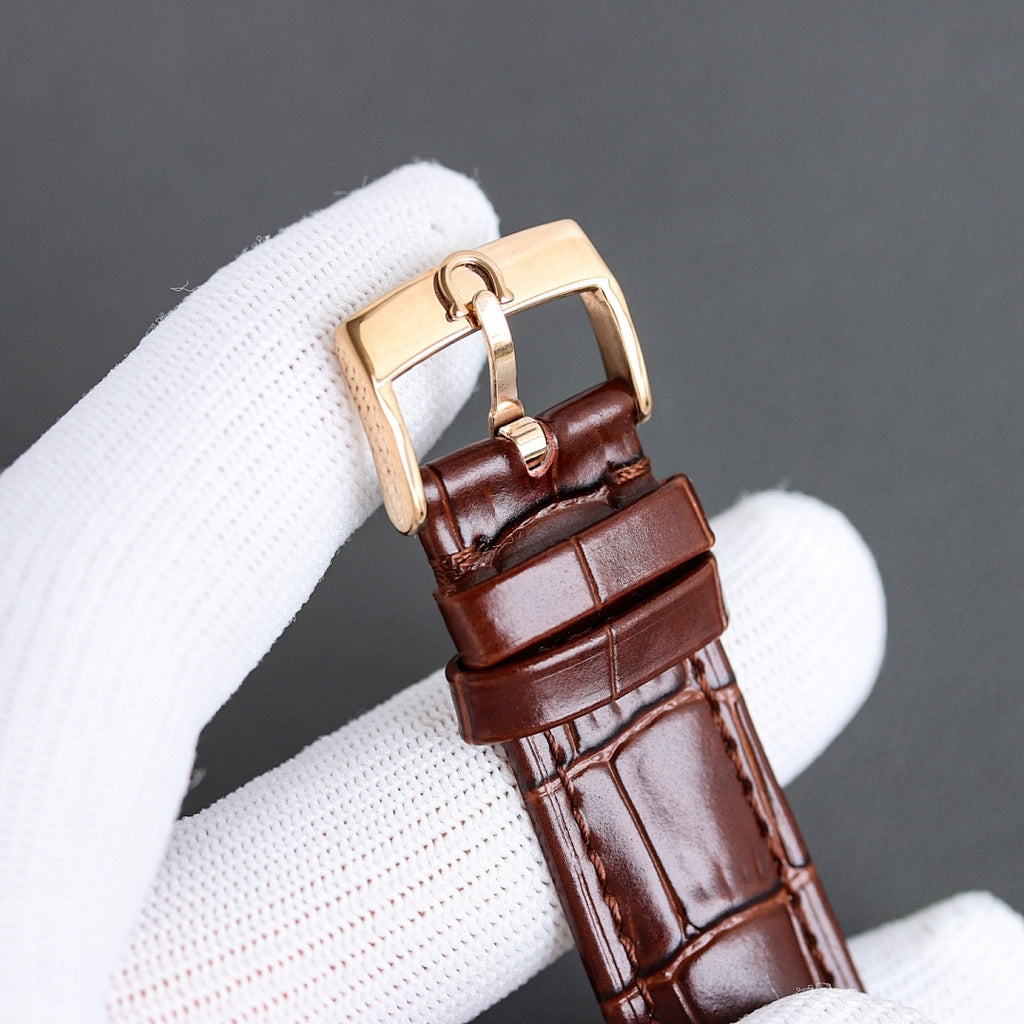 Luxury watch side view with brown leather strap and rose gold-toned case with rounded lugs