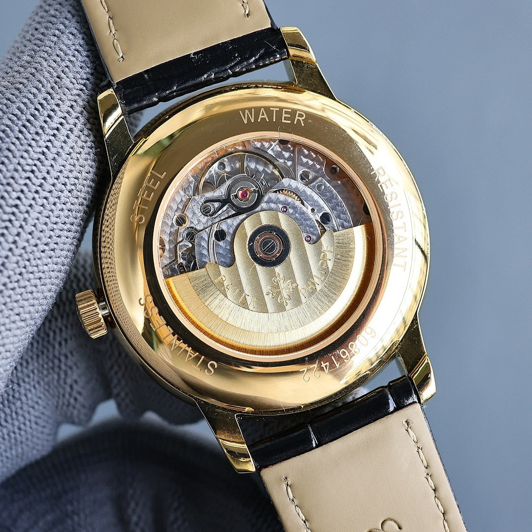 Gold watch with open caseback showing mechanical movement; beige leather strap.