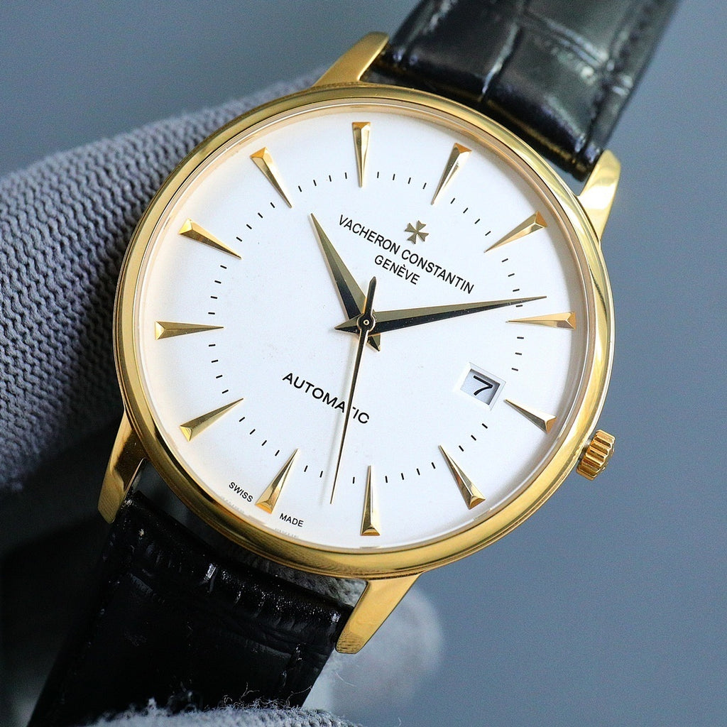Gold-tone automatic wristwatch with white dial, black leather strap, gold hour markers and hands.