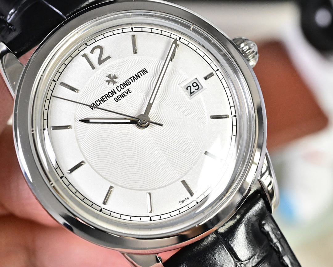 Wristwatch close-up of white dial with markers, gold-toned movement visible