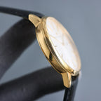 Vacheron Constantin wristwatch side view: gold case and white dial, black leather strap.