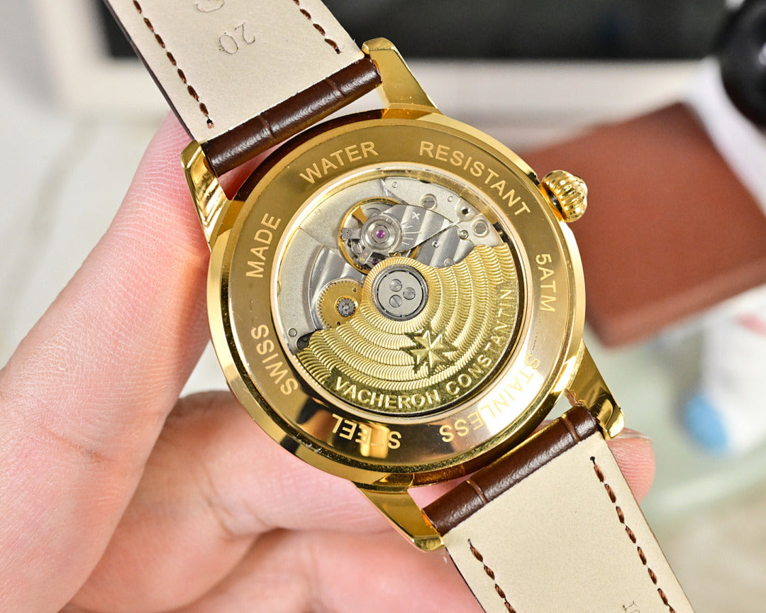 Gold-tone watch caseback with brown leather strap and stamped markings