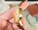 Gold-tone wristwatch side profile with brown leather strap