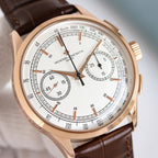 Close-up of round wristwatch face with brown leather strap and white chronograph dial