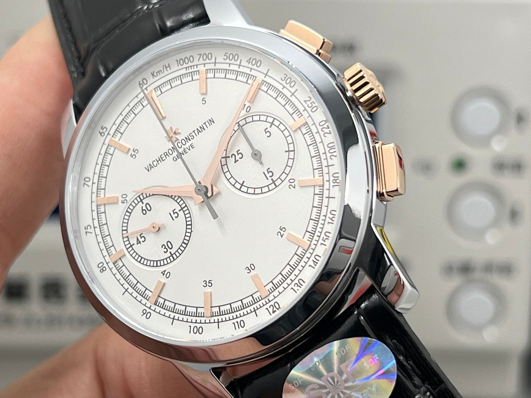 Chronograph wristwatch dial close-up with white face, tachymeter ring, subdials.