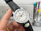 White dial chronograph wristwatch with black leather strap and iridescent case badge.