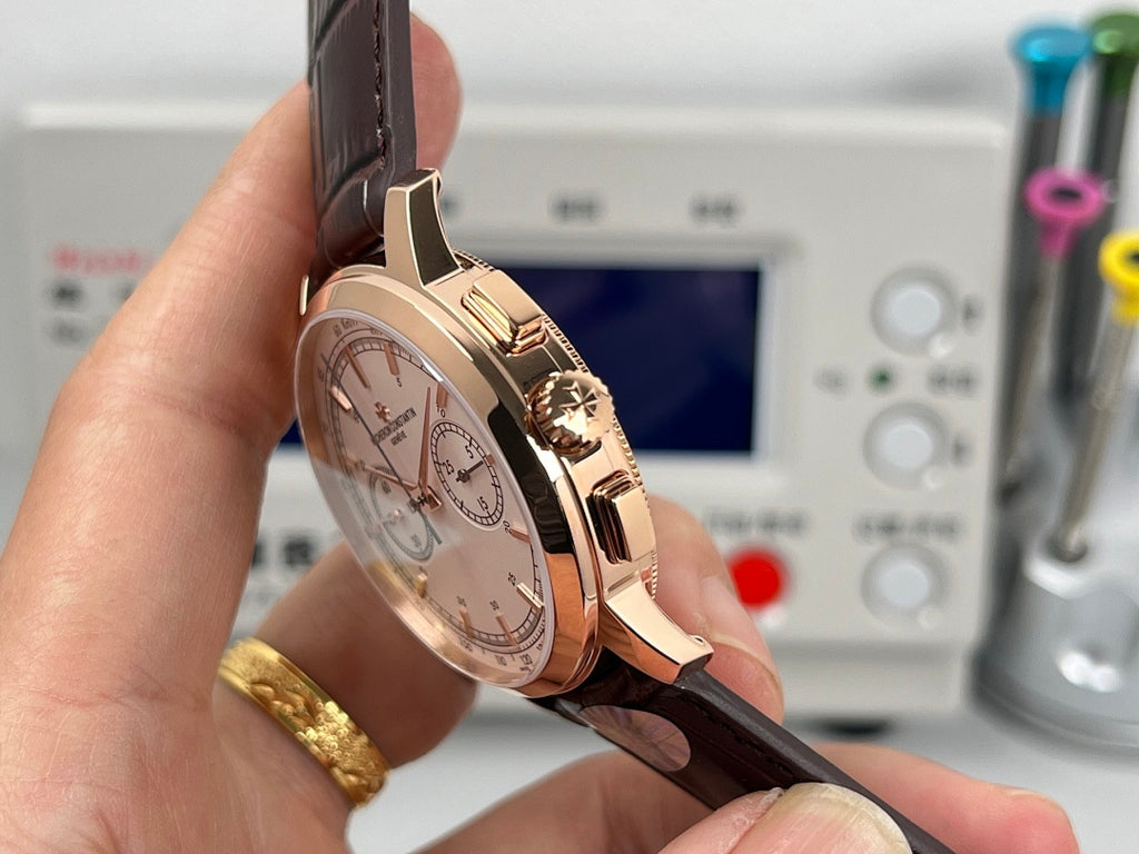 Rose gold tone chronograph watch with white dial and brown leather strap, side view
