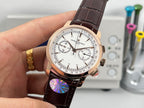 White dial chronograph watch with brown leather strap and rose gold case, front view