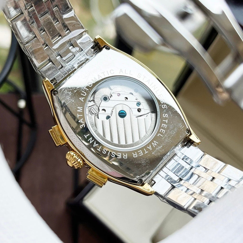 Two-tone wristwatch caseback with engraved back and visible mechanical movement.