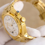 Gold watch case with crown and pushers, white dial visible on black strap