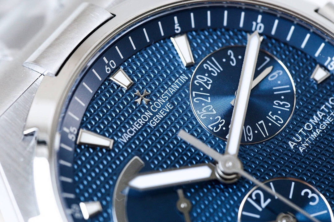 Close-up of blue textured watch dial with baton markers and multiple hands