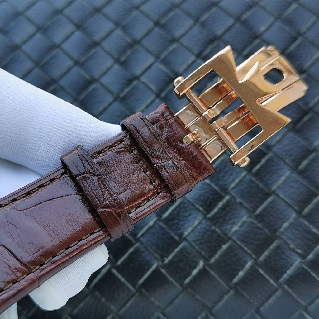Gold-tone watch clasp on brown leather strap with engraved keeper