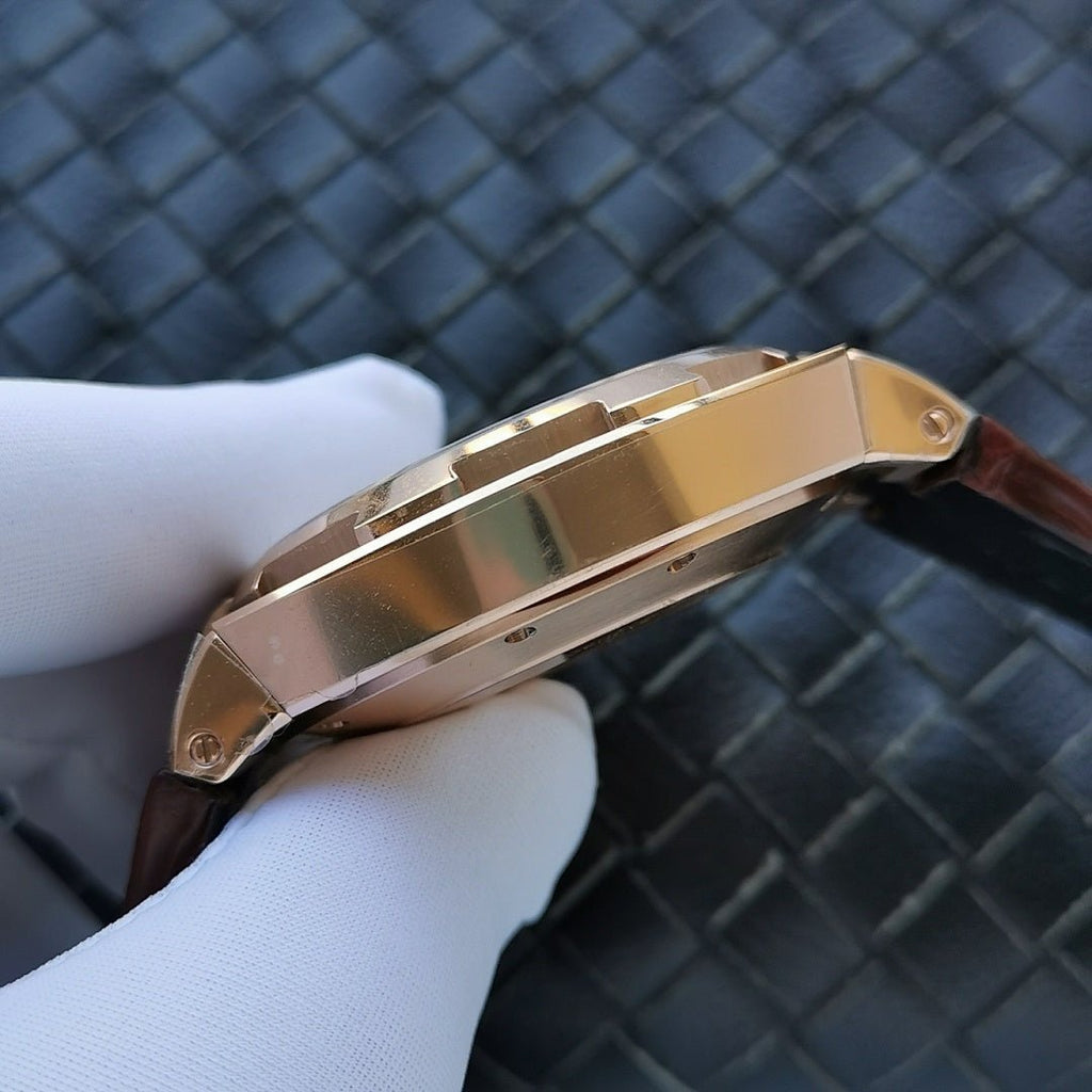 Gold-tone watch case side with reflective bezel on brown leather strap