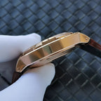Gold-tone watch case side with reflective bezel on brown leather strap