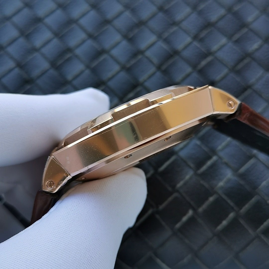 Gold-tone watch case side with reflective bezel on brown leather strap