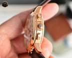 Rose gold wristwatch side profile with crown and pushers, brown leather strap