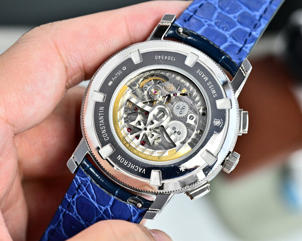 Round watch with exposed movement through the dial, blue leather strap and silver bezel.