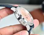 Wristwatch side view with silver case and black strap, held in a hand.