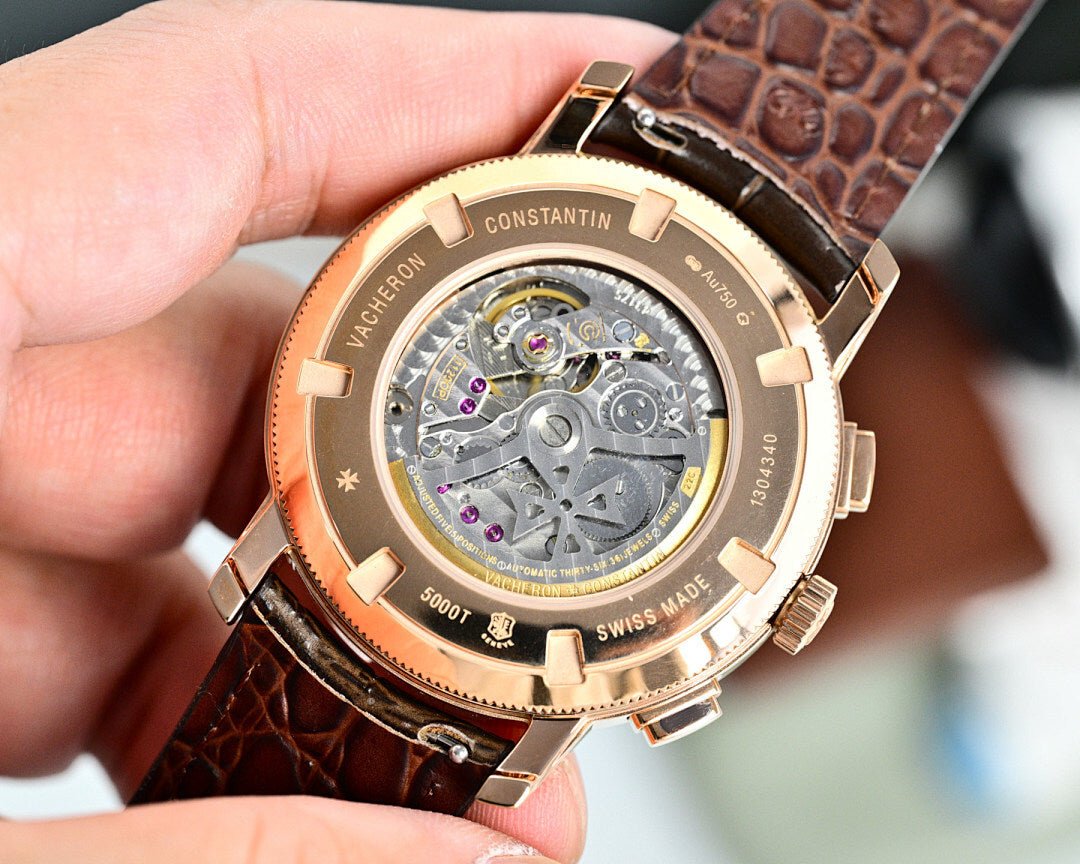 Vacheron Constantin watch caseback showing movement, brown leather strap and gold-tone bezel