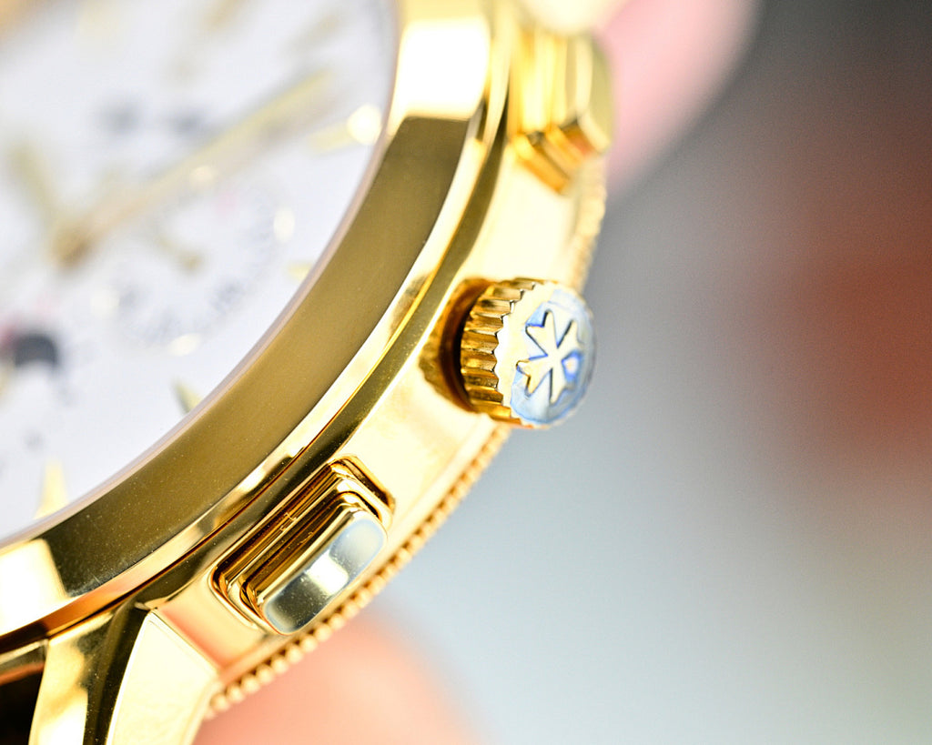 Gold-tone wristwatch crown and bezel detail with blue accent, leather strap edge