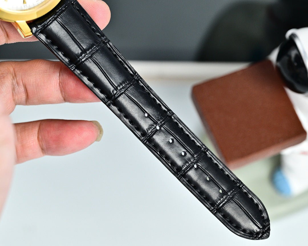 Black leather watch strap with stitched pattern and gold case connector