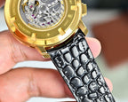 Close-up of gold watch case with visible movement, black leather strap