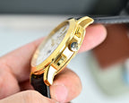 Gold wristwatch side view with crown and pushers, black leather strap