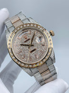 Rolex watch with sparkling dial, day/date window, gold-tone bezel, and metal bracelet.