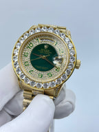 Rolex wristwatch with green dial, gold bezel, and diamond indices