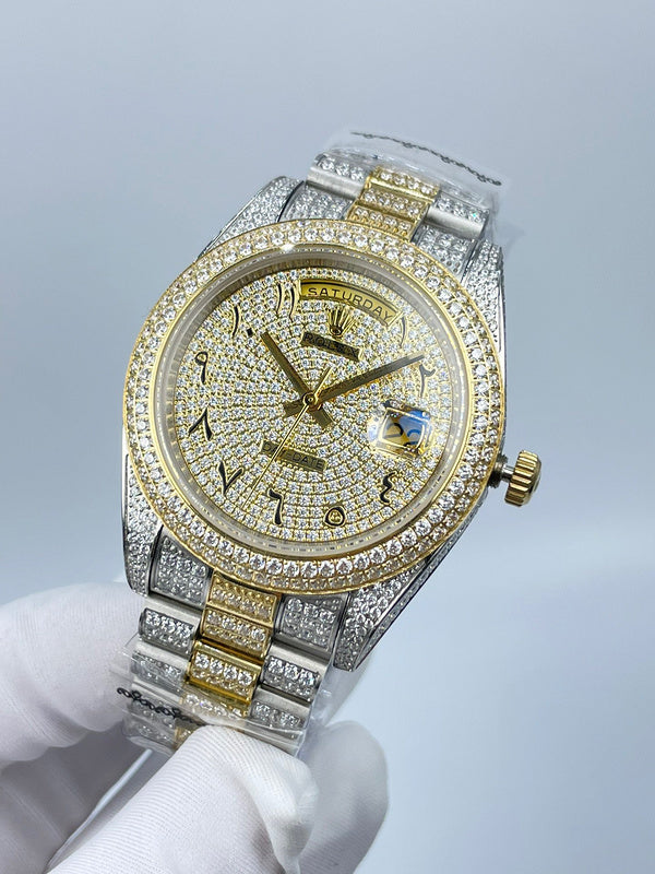 Rolex two-tone wristwatch with gold dial center, diamond bezel, and blue gem at 3 o'clock.