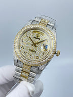 Rolex two-tone wristwatch with gold dial center, diamond bezel, and blue gem at 3 o'clock.