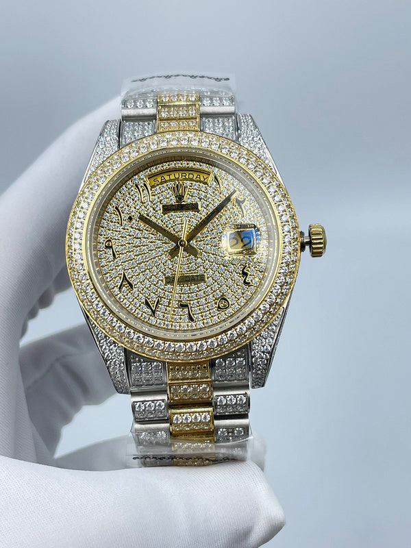 Rolex two-tone wristwatch with diamond bezel, blue dial detail, and gold accent center stripe on links.